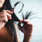 최신 ‘헤어 헬스’ 트렌드, 집에서 실천하는 건강한 머릿결 관리법 Woman examining split ends of hair with magnifying glass