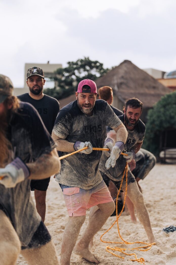 Photo by Will Haddock Men playing tug-of-war on a sandy beach